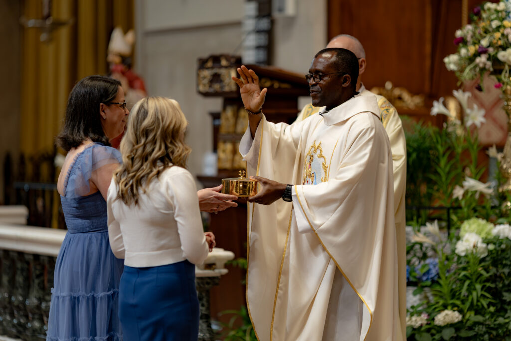 Priest blesses the wedding guests that presented the gifts at a beautiful Catholic Wedding in the Cathedral Basilica of St. Augustine.