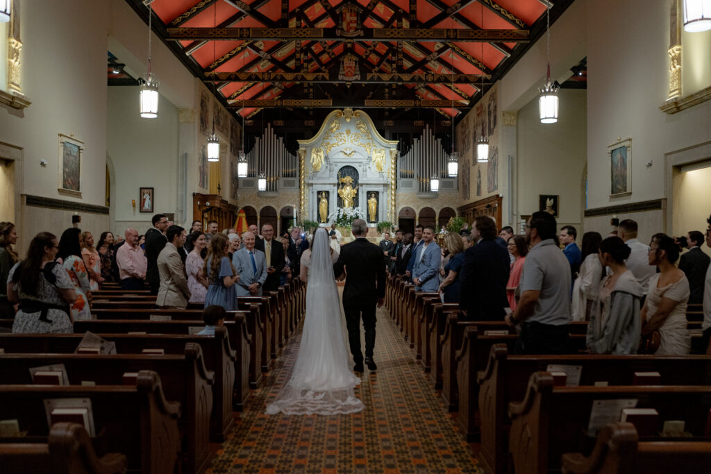 Bride and her father process down the aisle at the Cathedral Basilica of St. Augustine, Florida.