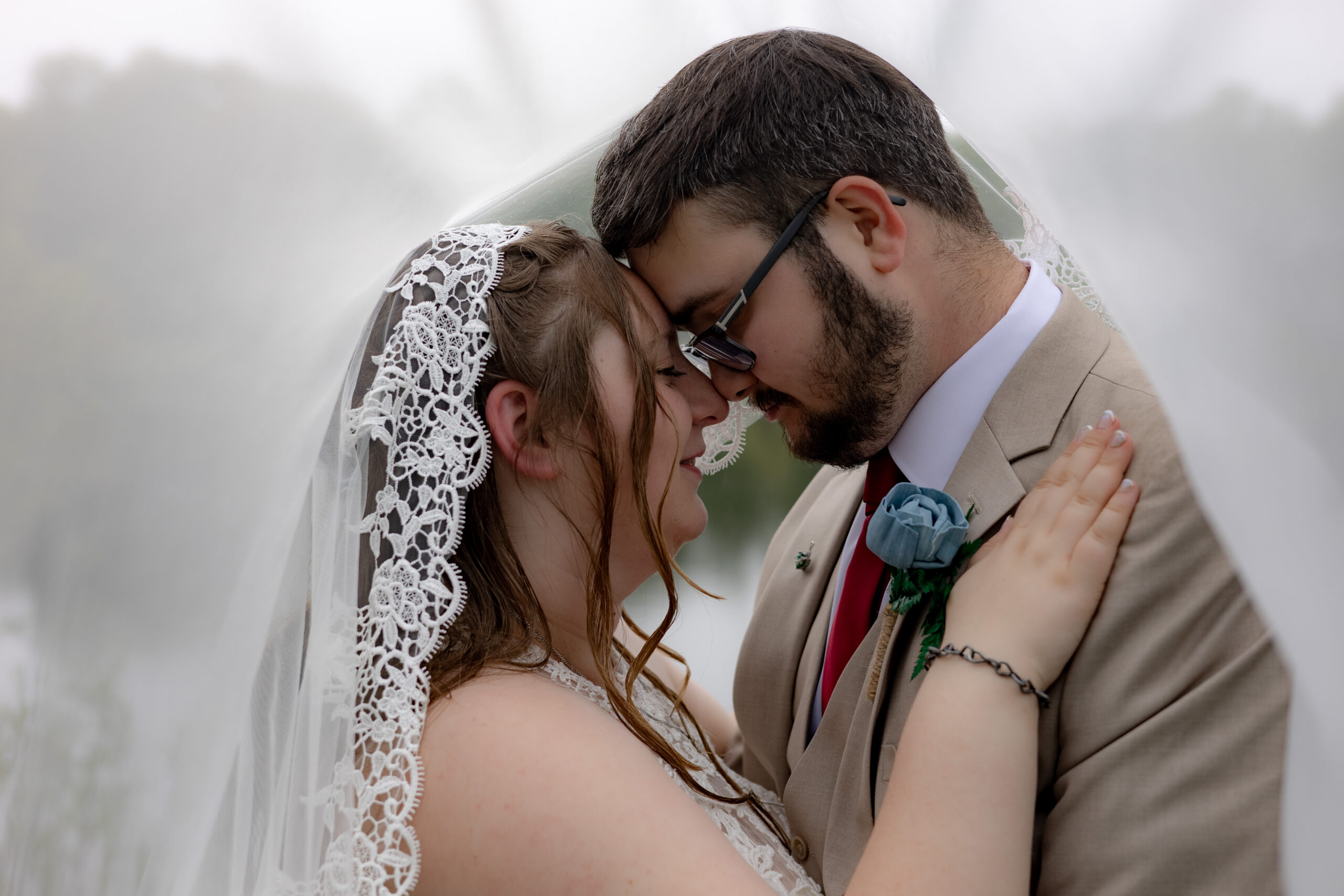 Bride and Groom share an intimate moment under the veil in the rain.