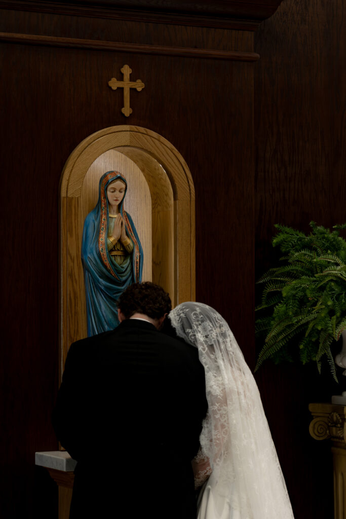 Bride and Groom honor Mary by bringing flowers to her during their Catholic Wedding Mass at Little Rose Catholic Church in Toledo, OH.