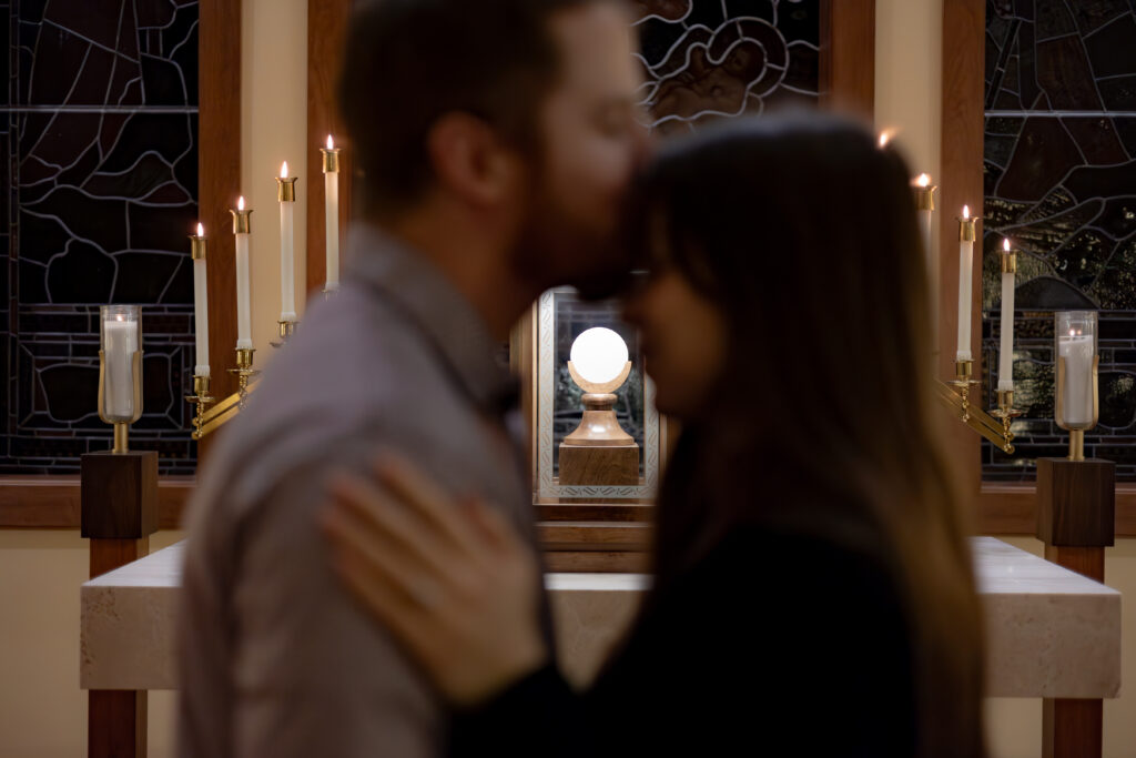 Catholic couple shares an intimate moment after proposal in front of Eucharistic Adoration.